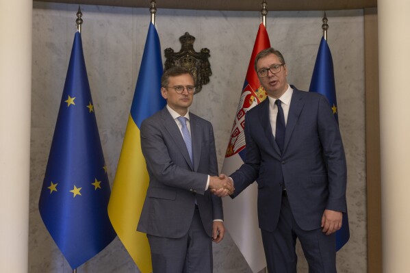 Serbian President Aleksandar Vucic, right, shakes hands with Ukraine's Foreign Minister Dmytro Kuleba, left, in Belgrade, Serbia, Monday, May 13, 2024. Kuleba, who has arrived on a surprise visit to Russia-friendly Serbia, held talks on Monday in Belgrade in a sign of warming relations between the two states. (AP Photo/Marko Drobnjakovic)